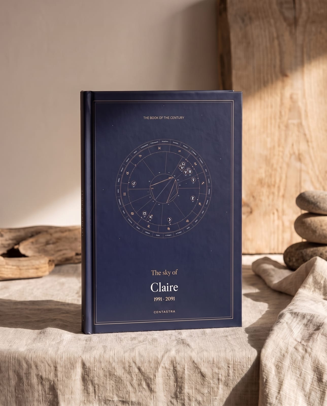 The Centastra hardback book, navy cover with its celestial chart, resting on ivory linen