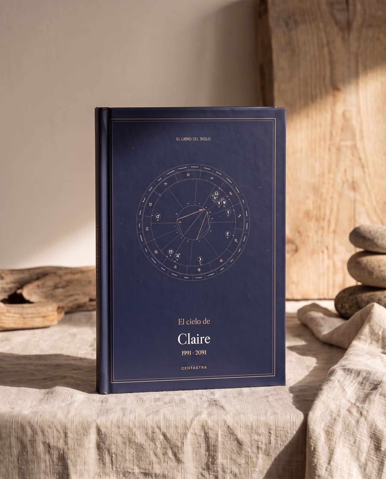 El libro de tapa dura de Centastra, cubierta azul noche con su carta celeste, sobre lino marfil